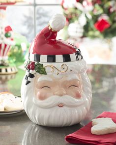 a santa clause cookie jar sitting on top of a table next to cookies and candy