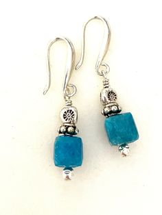 Raw petrol blue apatite earrings with Thai fine silver accents on artisan solid sterling silver ear hooks.  Beautiful greenish blue natural apatite faceted gemstone cubes are 9mm and accented with Karen Hill Tribe fine silver triangular beads and sterling silver.  Gemstones hang from handmade artisan solid .925 sterling silver ear hooks. Total drop is 1 1/4 inches. Perfect pop of eye catching blue on short artsy ear wires! Turquoise Apatite Gemstone Earrings, Blue Apatite Gemstone Earrings, Handmade Blue Apatite Earrings, Silver Apatite Dangle Earrings, Blue Apatite Earrings Gift, Blue Apatite Earrings For Gift, Blue Earrings For Gift, Turquoise Gemstone Earrings, Aquamarine Earrings