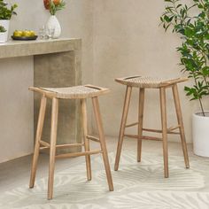 two wooden stools sitting next to each other in front of a counter with potted plants