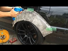 a person using a spray bottle to clean the rim of a car