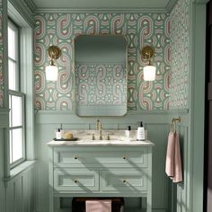 a bathroom with green and pink wallpaper, white sink and gold faucet