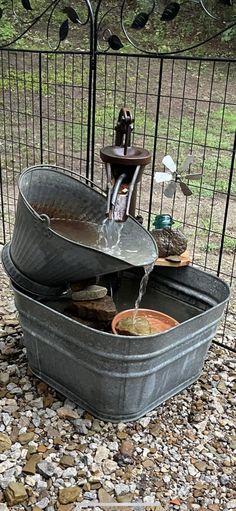 a metal tub filled with water next to a fence