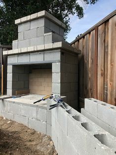 a brick oven built into the side of a building with cement blocks and tools in it