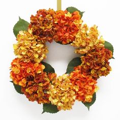 an orange and yellow wreath hanging on a white wall