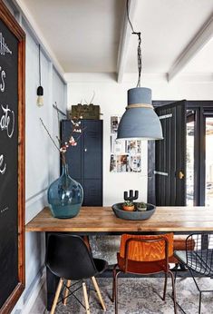 a dining room table with two chairs and a chalkboard on the wall behind it