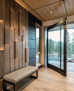 a bench sitting in front of a wooden wall with glass doors leading to the outside