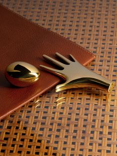 a gold fork and knife rest on top of a brown leather case