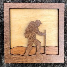 a wooden cutout of a hiker with a stick in his hand on a granite surface