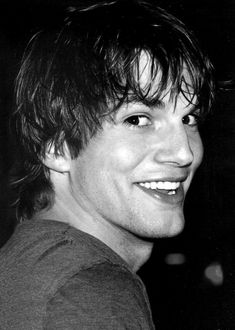 a black and white photo of a young man smiling at the camera with his eyes wide open