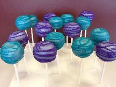 there are many blue and purple lollipops on the white cake platter