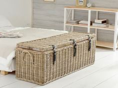 a wicker storage box sitting on top of a white floor next to a bed