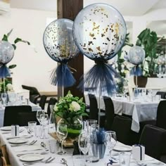 the table is set with silver and white decorations for an event or celebration, while balloons are floating in the air