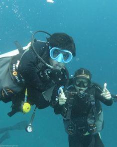 two scuba divers giving thumbs up in the water