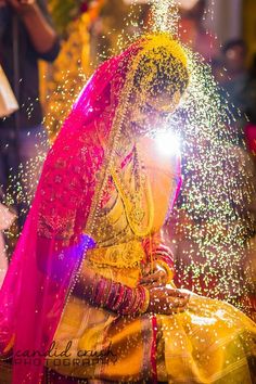 a woman in yellow and pink dress sitting down with sparkle coming out of her hair