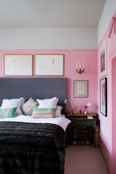 a bedroom with pink walls and black bedding