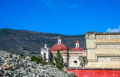 an old building with two red domes on top and some rocks in the foreground