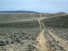 two people walking down a dirt road in the middle of nowhere