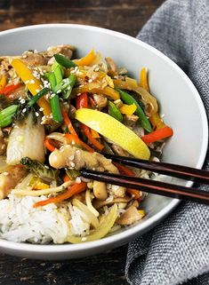 a white bowl filled with rice, vegetables and meat on top of a wooden table