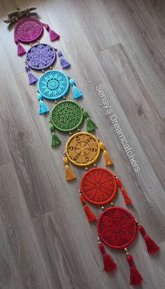 a row of colorful crocheted wall hangings with tassels on them