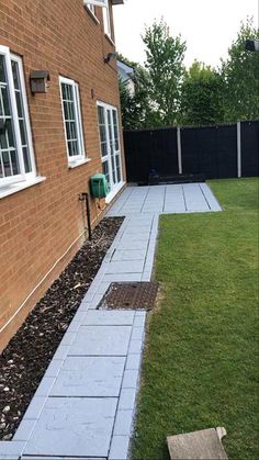 a brick house with grass in the front yard and walkway leading up to the back door