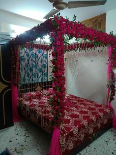 a bed covered in red and pink flowers next to a ceiling fan