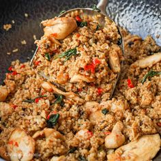 a close up of food in a bowl with a spoon on top of rice and chicken