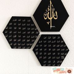 two black and gold wall hangings with arabic writing on the top one has an eiffel tower in the middle