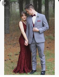 a man and woman standing next to each other in front of trees wearing formal wear