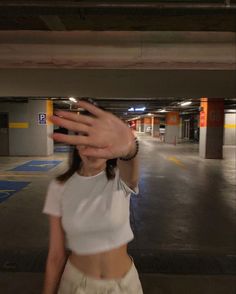 a woman is holding her hand up to take a selfie in a parking garage