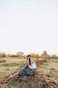 a woman sitting on top of a dry grass field