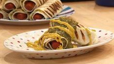 two plates with hotdogs wrapped in cheese and mustard on them, sitting on a table