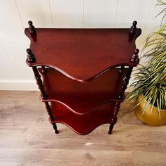 a wooden side table sitting next to a potted plant