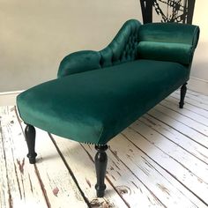 a green couch sitting on top of a wooden floor next to a black chair and clock