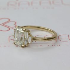 an emerald cut diamond ring sitting on top of a piece of paper