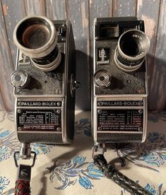 two old fashioned cameras sitting next to each other