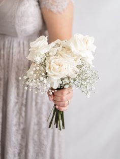 a woman holding a bouquet of white flowers