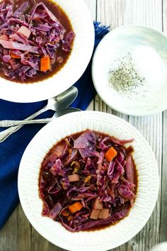 two white bowls filled with red cabbage and carrots on top of a wooden table