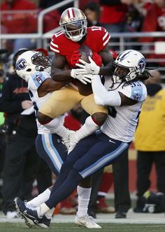 a football player is being tackled by two other players