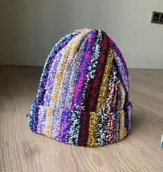 a multicolored hat sitting on top of a wooden floor next to a pair of shoes