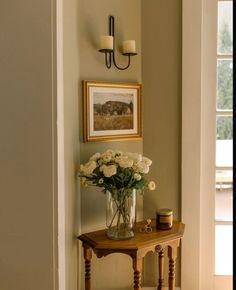 a vase filled with white roses sitting on top of a table next to a window