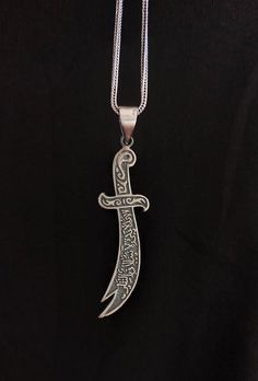 Zulfiqar Arabic Written Islamic Men Necklace Due to the issues in supply, the chain that is going to be send will be a different one but very similar to the picture. You can contact us for more detail. Perfect Silver Islamic-Muslim pendant, the sword of Ali.  The sword called as Zulfiqar. It is a 925 sterling real silver and handmade. A special gift for Muslim men for birthdays and special days. If you have a question please don't hesitate to contact me. Material: 925 Sterling Silver Size: 1*6 cm-5.9cm / 0.62*2,32 in Chain Lenght :55 cm / 21.65 in Weight: 12.40 gr Story of This Meaningful Sword: Alī ibn Abī Ṭālib showed a lot of heroism in the battle of Uhud.  While trying to protect the Prophet in battle, his sword is broken.  Seeing this, our Prophet gave him his sword, Zulfikar.  With h Islamic Necklace Men, Battle Of Uhud, Islamic Necklace, Muslim Men, Imam Ali, Men Necklace, Special Gift, Special Gifts, Valentine Day Gifts