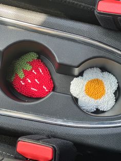 two crocheted eggs and an egg in a car cup holder with strawberries