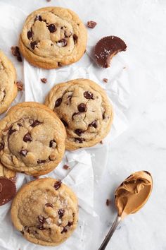 chocolate chip cookies on wax paper with spoon and jar of peanut butter in the background