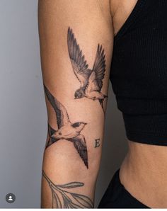 a woman's arm with two birds on it and one bird flying in the air