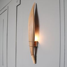 a light that is on the wall next to a wooden object with a long curved blade