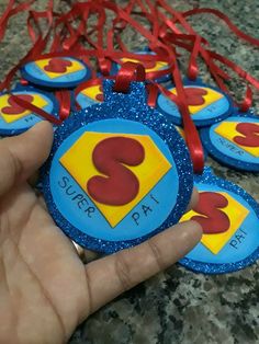 a hand holding some blue and yellow badges with red ribbons around them on a table