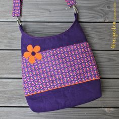 a purple purse with an orange flower on it