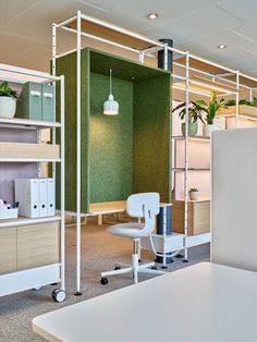 an office cubicle with chairs, desks and shelves filled with plants in it