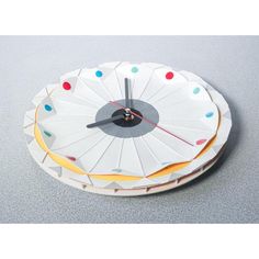 a white clock with multicolored circles on it's face sitting on top of a table