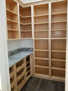 an empty walk in closet with wooden shelves and marble counter tops, along with wood flooring